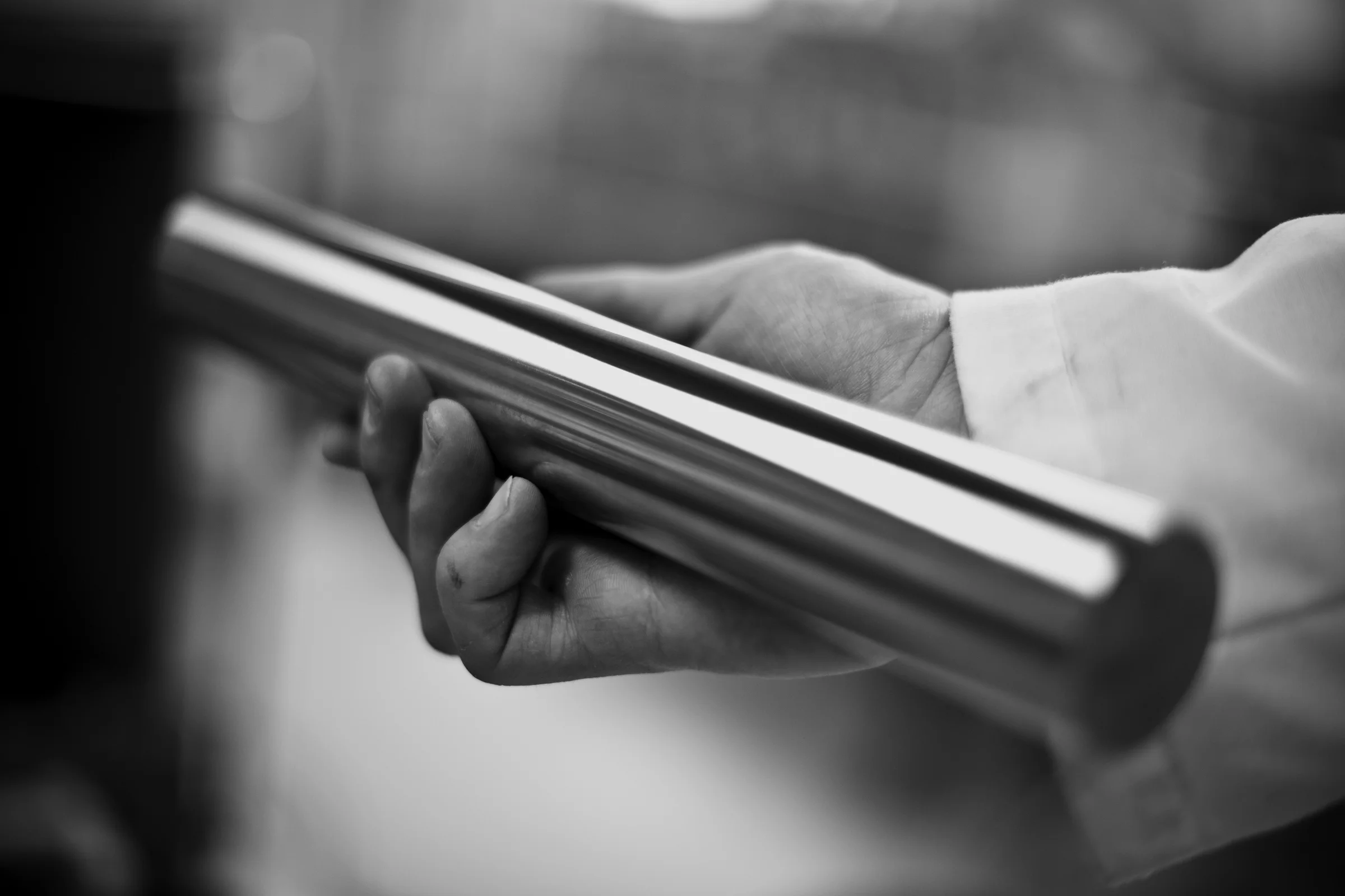 A hand holds a polished coated steel rod in Savroc's laboratory, black and white